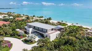 Ein modernes Strandgrundstück mit einem großen Haus, einem Pool und Meerblick.