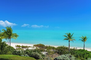 Ein Strand mit klarem türkisblauem Wasser, weißem Sand und Palmen.