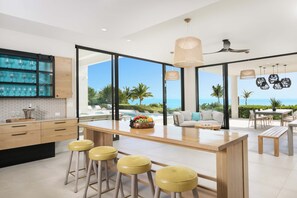Een moderne keuken met een groot eiland, barkrukken en uitzicht op de oceaan.