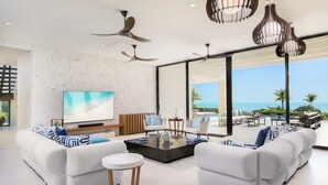 Ein modernes Wohnzimmer mit einem großen Flachbildfernseher, zwei Sofas, einem Couchtisch und Deckenventilatoren.