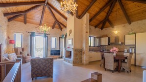 A spacious living area with a fireplace, wooden ceiling beams, and a dining table with wicker chairs. - Afrati villa (Zakynthos)