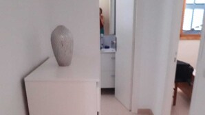 Un couloir étroit avec un réfrigérateur blanc et un vase posé sur le dessus.