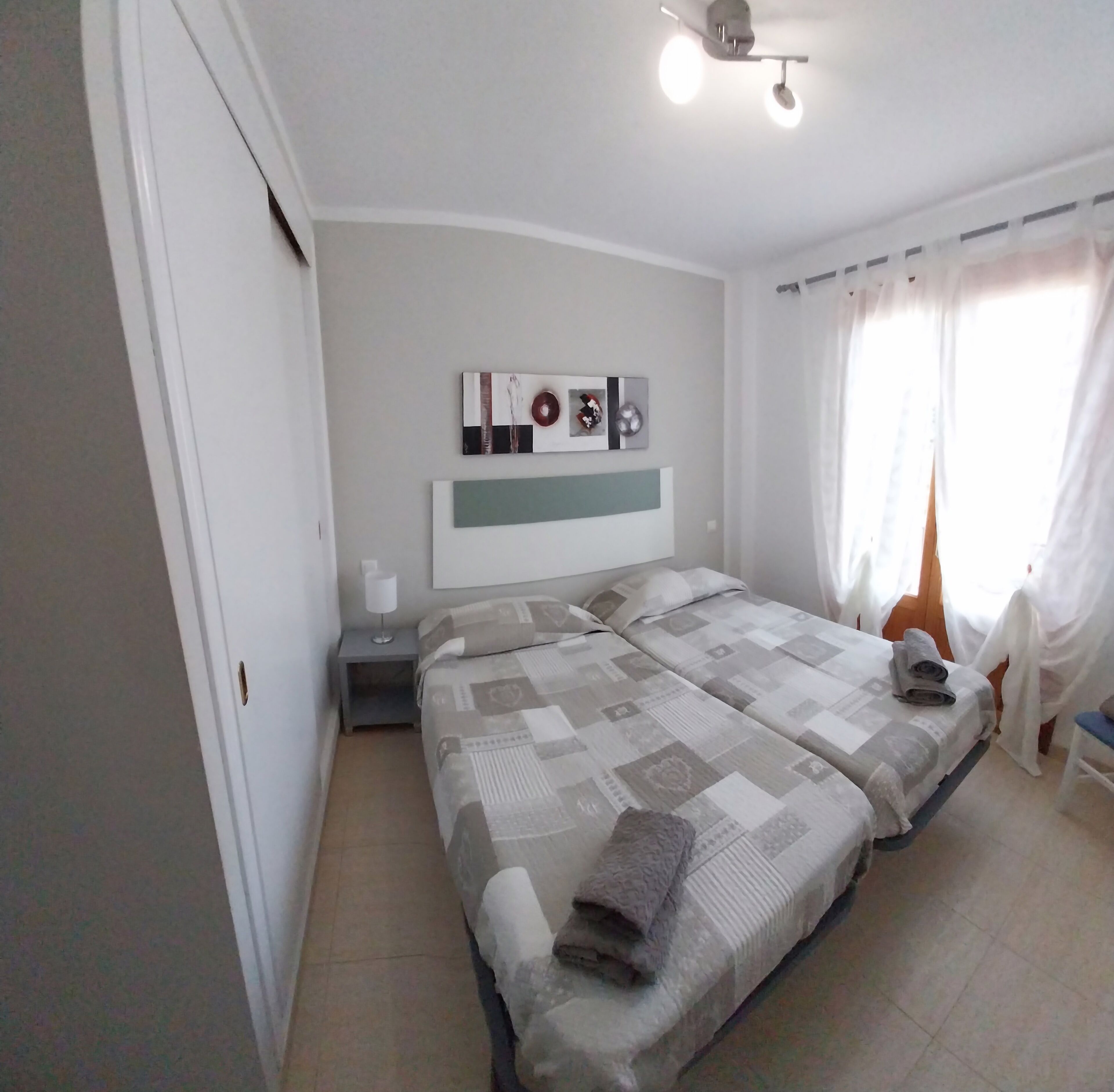Camera da letto con due letti, un comodino, una lampada a parete e un ventilatore a soffitto.