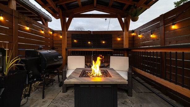 An outdoor patio with a fire pit, a grill, and wicker furniture under a wooden pergola. - West Seattle Driftwood Cottage - Firepit + Walk to Coffee & Restaurants (Seattle)