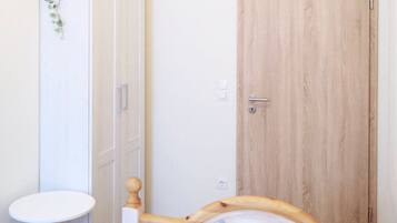 A bedroom with a bed, a wardrobe, a small round table, and a wooden door.