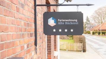 Señal para 'Ferienwohnung Alte Bäckerei', con un edificio de ladrillo y un pequeño jardín.