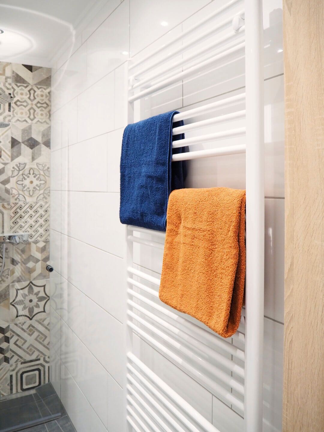 Ein Badezimmer mit einem weißen Handtuchhalter, der zwei Handtücher trägt, eines blau und eines orange.
