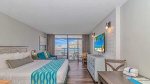 A hotel room with a bed, a desk, a chair, a TV, and a balcony with a city view. - Landmark 607 (Myrtle Beach)