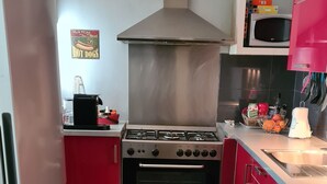 Cocina con estufa de acero inoxidable, refrigerador y armarios rojos.