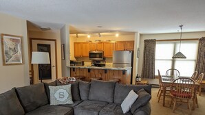 A living room with a sectional sofa, a coffee table, and a dining area with wooden chairs and a table.