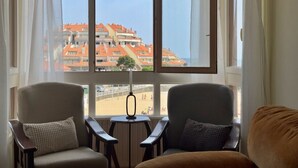 Una habitación con dos sillones mirando hacia una ventana grande con vistas a una playa y edificios.