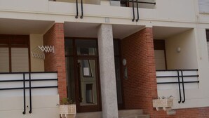 A building with a central entrance, a brick facade, and a balcony with black railings.