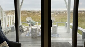 A covered outdoor seating area with two white chairs and a table, overlooking a grassy landscape. - Amelia Island oceanfront home on Sandpiper Loop, amazing views & steps to ocean (Fernandina Beach)