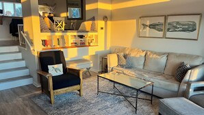 A living room with a sofa, armchairs, a coffee table, and a bookshelf. - Amelia Island oceanfront home on Sandpiper Loop, amazing views & steps to ocean (Fernandina Beach)
