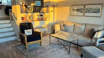 Un salon comprenant un canapé, des fauteuils, une table basse et une bibliothèque.
