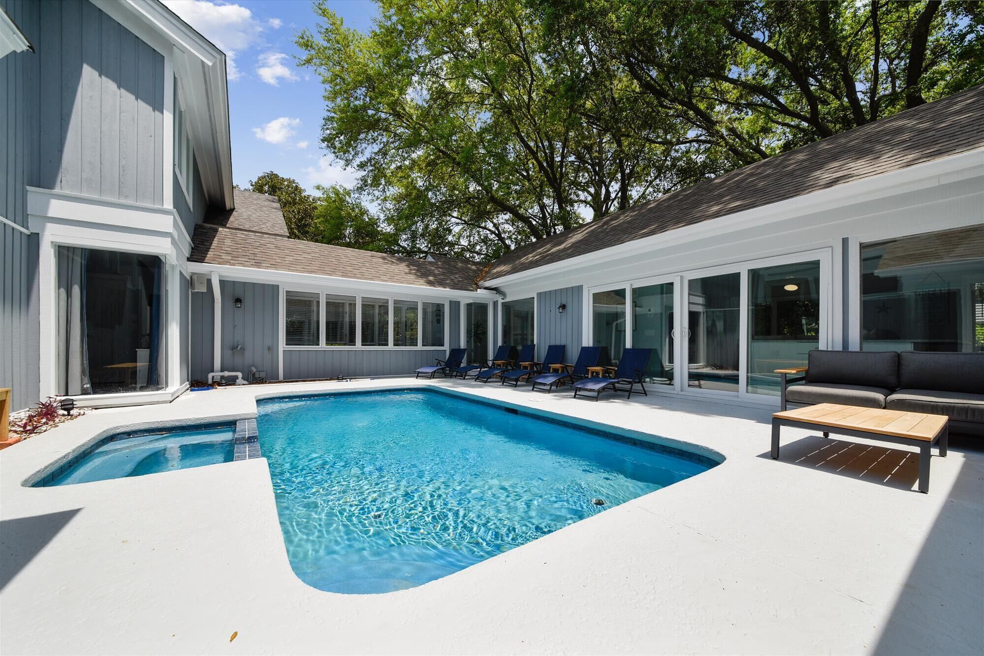 A modern outdoor pool area with a built-in pool, lounge chairs, and a seating area with a table.
