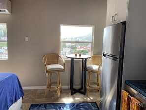 Enjoy a city view from the comfort of your room, featuring a compact kitchen area with a refrigerator, table, and chairs.
