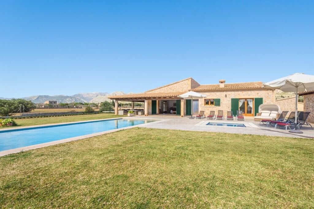 A house with a swimming pool, outdoor seating, and a view of mountains.