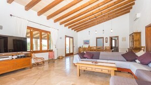 Un salon spacieux avec un plafond en bois, un grand canapé, un téléviseur et un meuble en bois.