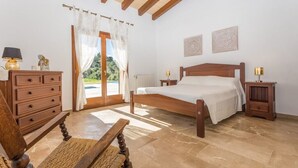Une chambre avec un lit en bois, une commode en bois, une table de chevet et une chaise.