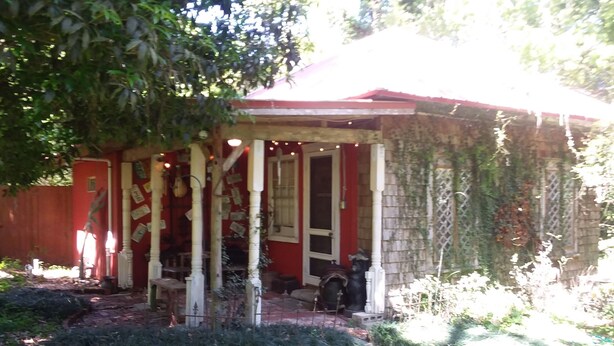 A red building with a porch, columns, and a dog. - CARRIAGE HOUSE (Monticello)