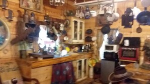 A rustic kitchen with wooden walls, a bar area, and various kitchen utensils and appliances. - CARRIAGE HOUSE (Monticello)