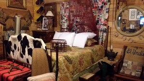 A cozy room with a bed, a chair, a small table, and a mirror. - CARRIAGE HOUSE (Monticello)