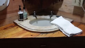 A bathroom with a wooden vanity, a sink with a mirror, and two bottles of soap. - CARRIAGE HOUSE (Monticello)