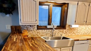 A modern kitchen with a wooden countertop, white cabinets, and a window above the sink. - Best Pricing on the Main Channel at the Lake! (Osage Beach)