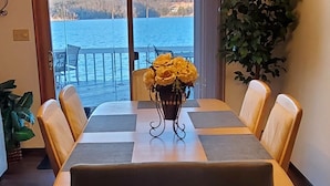 A dining area with a table set for four, a view of the water, and a plant on the right. - Best Pricing on the Main Channel at the Lake! (Osage Beach)