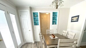 A dining room with a wooden table and chairs, a chandelier, and built-in shelves with decorative items. - 4 BR beach house 2 blocks from ocean in Cherry Grove! Dog friendly! (North Myrtle Beach)