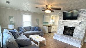 A living room with a gray sectional sofa, a white coffee table, and a fireplace. - 4 BR beach house 2 blocks from ocean in Cherry Grove! Dog friendly! (North Myrtle Beach)