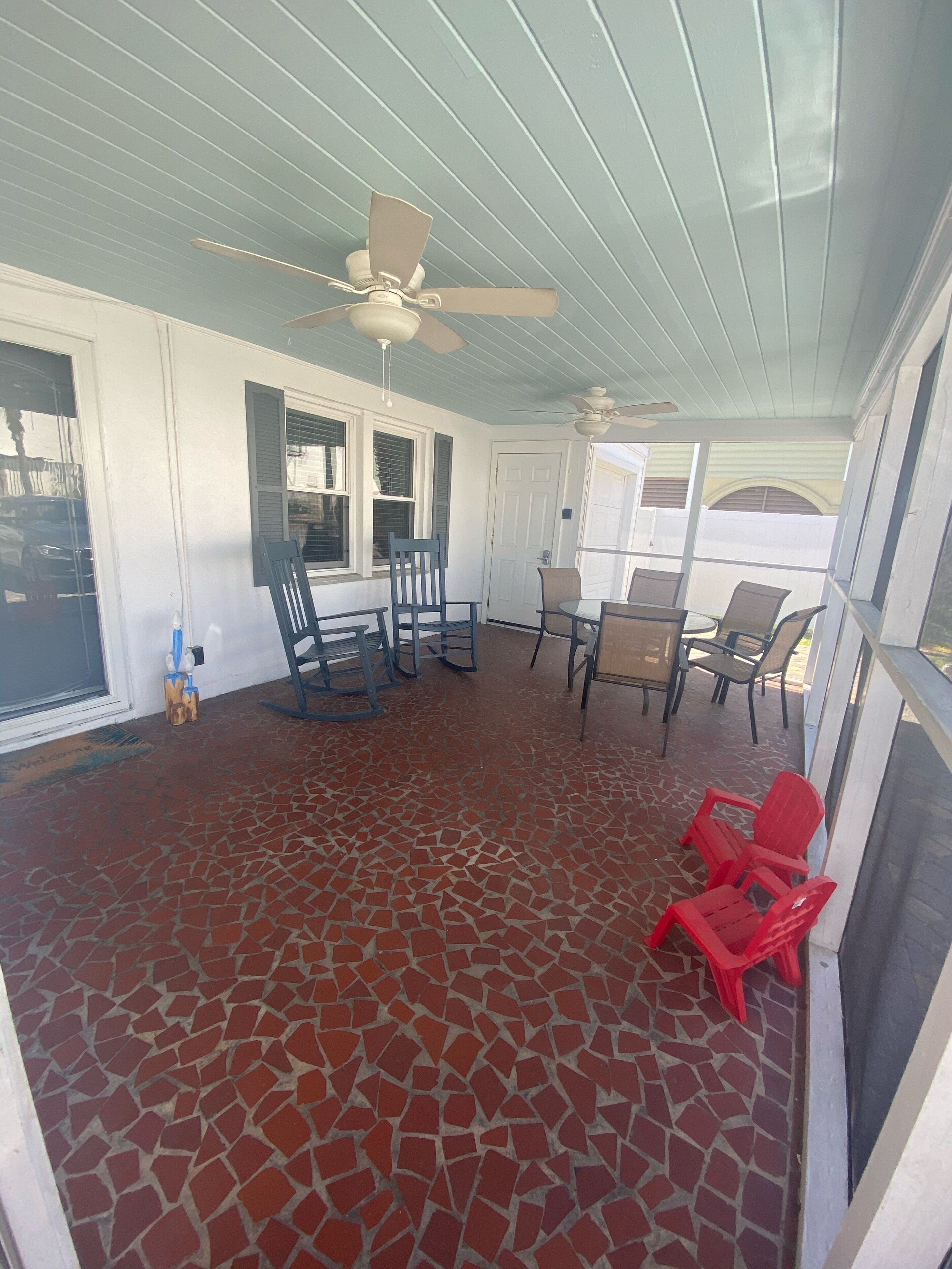 A covered patio with a mosaic floor, ceiling fans, and outdoor furniture.