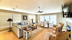A spacious living room with a sofa, coffee table, and dining area. - Seaport Village 1457 - Second Row in Garden City Beach (Garden City Beach)
