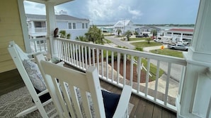 A balcony with white railings and a view of a residential area with houses and parked vehicles. - Seaport Village 1457 - Second Row in Garden City Beach (Garden City Beach)