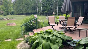 Un patio amueblado con mobiliario exterior, una chimenea y un jardín exuberante.