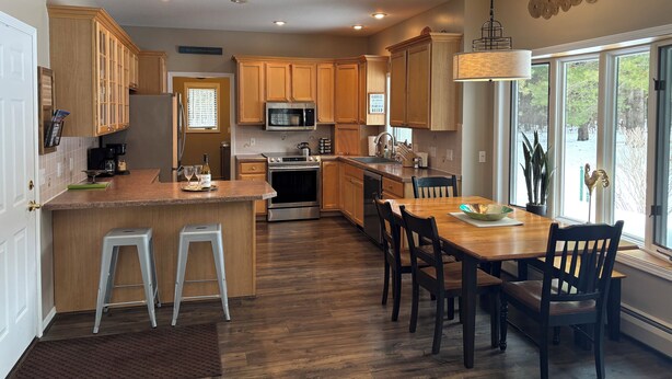 Una cocina moderna con armarios de madera, electrodomésticos de acero inoxidable y un comedor con un ventanal grande.