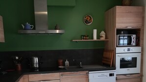 A modern kitchen with wooden cabinets, a dishwasher, a microwave, and a stove. - Maison de Village Agréable à Vivre (Précy-le-Sec)