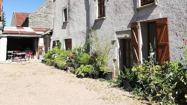 A rustic building with a stone facade, multiple windows, and a visible antenna. - Maison de Village Agréable à Vivre (Précy-le-Sec)