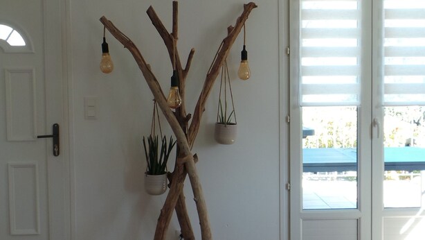 Una habitación de diseño moderno, con una lámpara de forma de árbol, un banco y vistas a través de una puerta.
