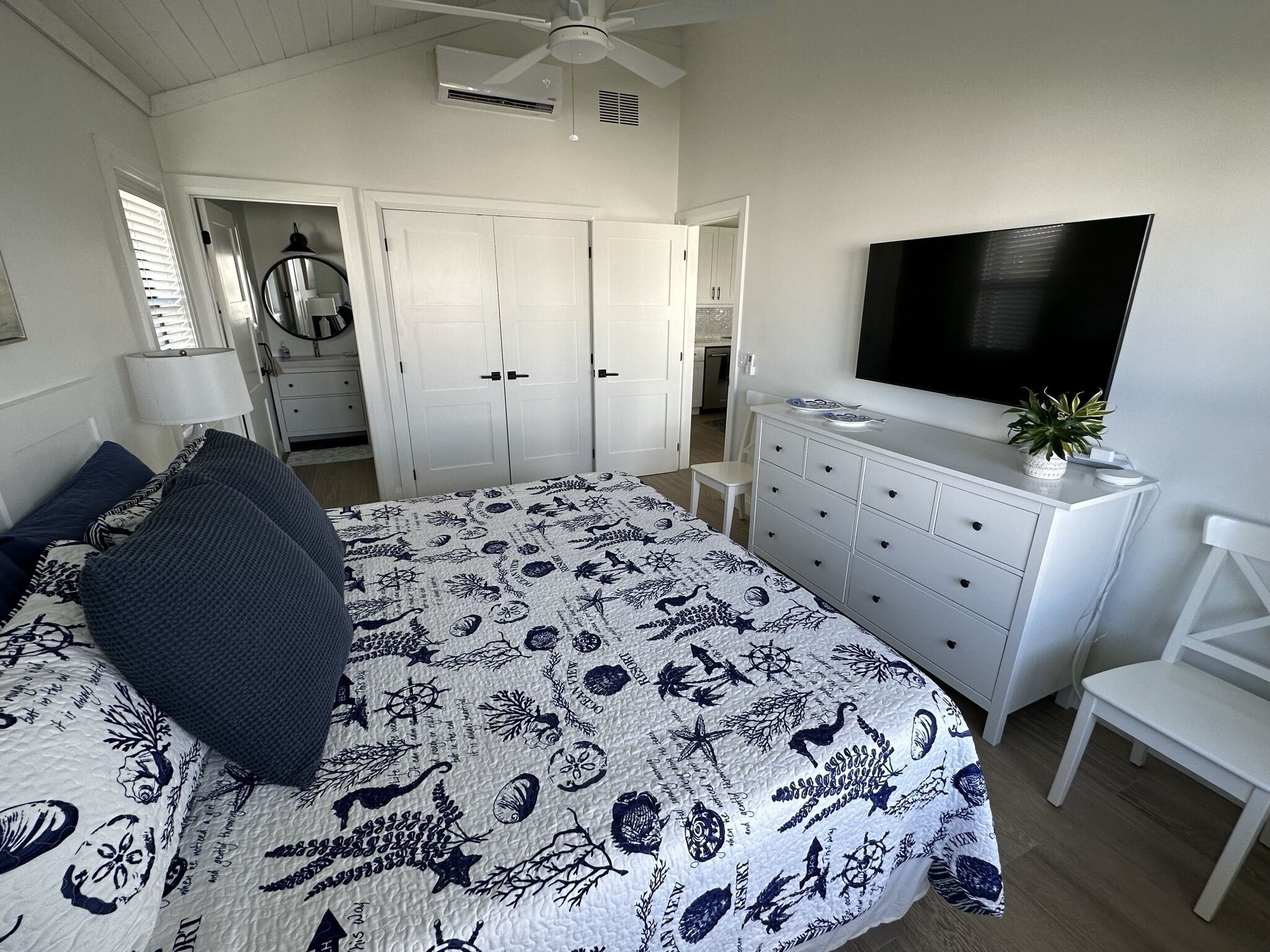 Quarto com cama, cômoda, televisão e ventilador de teto.