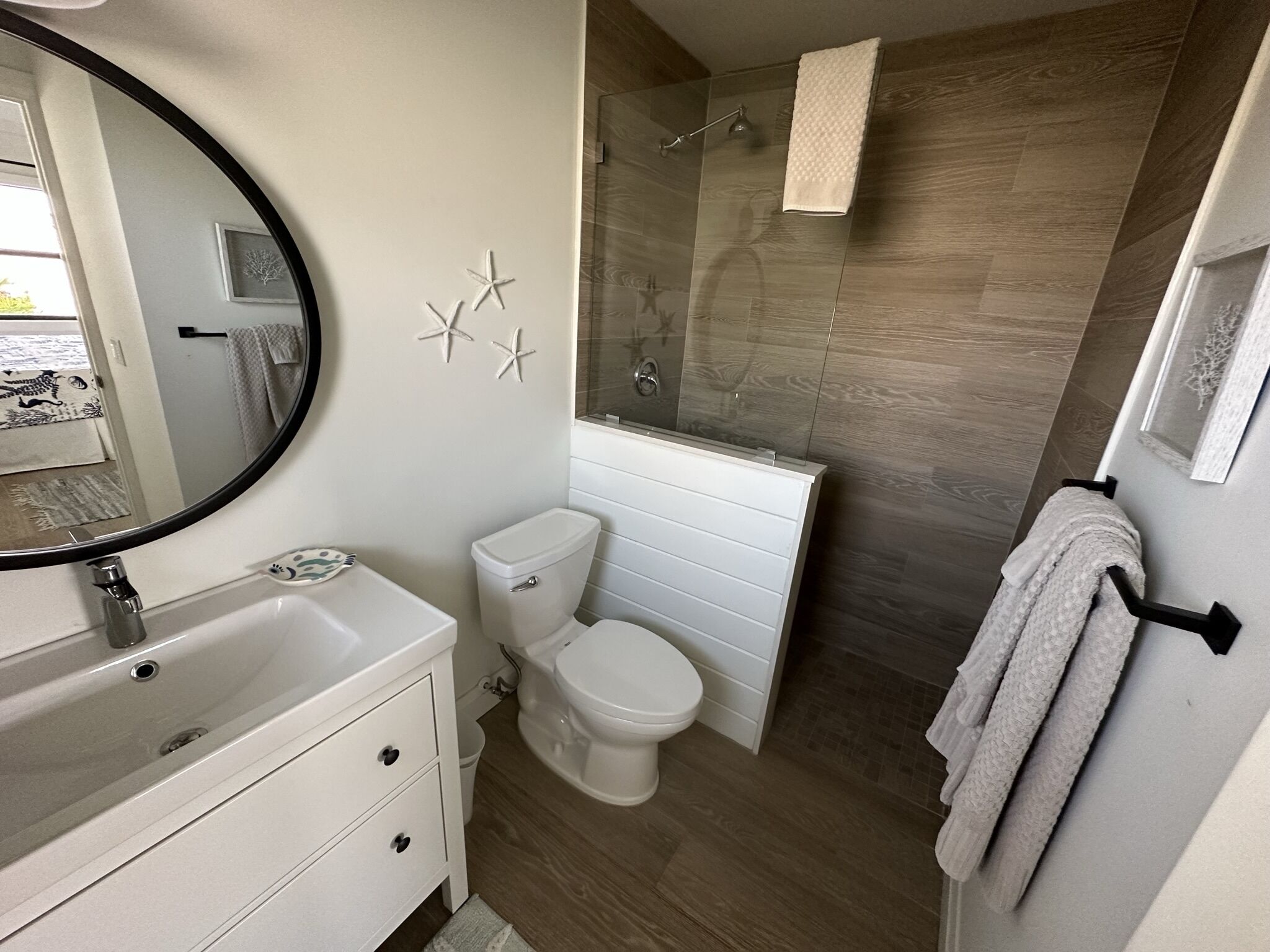 A modern bathroom with a white vanity, a toilet, a shower with a glass door, and a towel rack.
