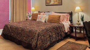 Ein Schlafzimmer mit einem geblümten Bettüberwurf, einer Chandelüster, einem Bild an der Wand und zwei Nachttischlampen.