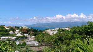 Une ville côtière avec des immeubles d’habitation, un ciel bleu dégagé et des montagnes à l’horizon.