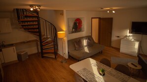 Un salon moderne avec un escalier, un canapé, une table à manger et un téléviseur.