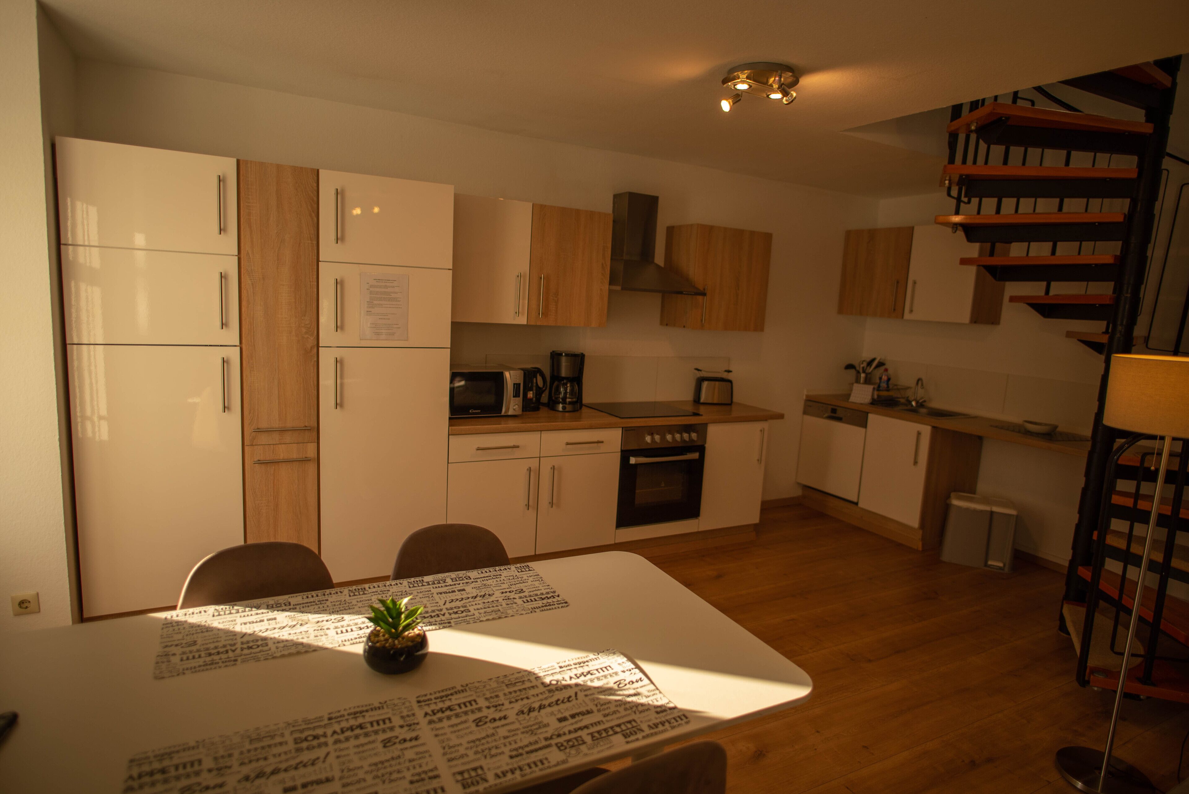 A compact kitchen with wooden cabinets, a stove, and a coffee maker.