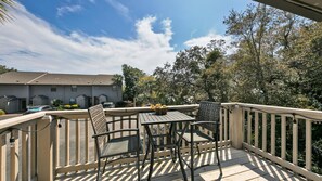 Une terrasse extérieure couverte, dotée d’une table et de chaises, et entourée d’une balustrade en bois.