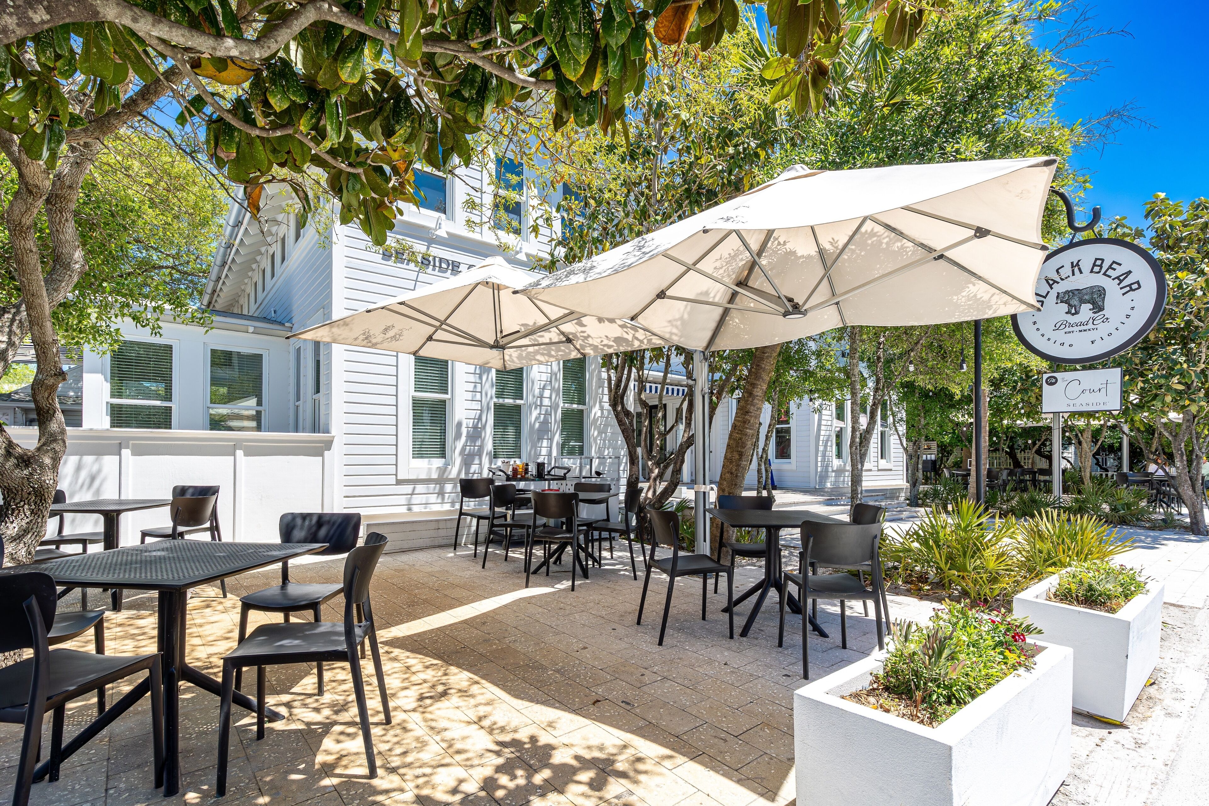 An outdoor patio area with tables and chairs, umbrellas, and planters.