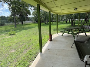 Relax in a serene outdoor setting with a picnic table and cushioned bench amidst lush greenery.