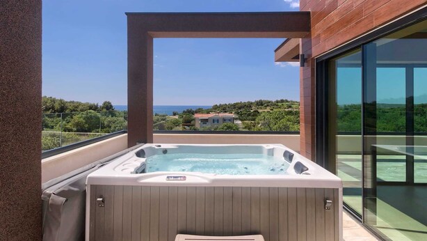 Ein Whirlpool auf einem Balkon mit freiem Blick auf das Meer und die umliegende Landschaft.
